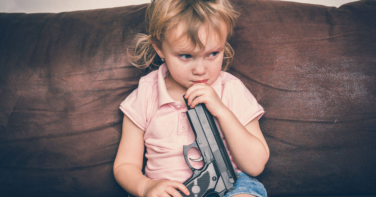 Child holding gun on couch