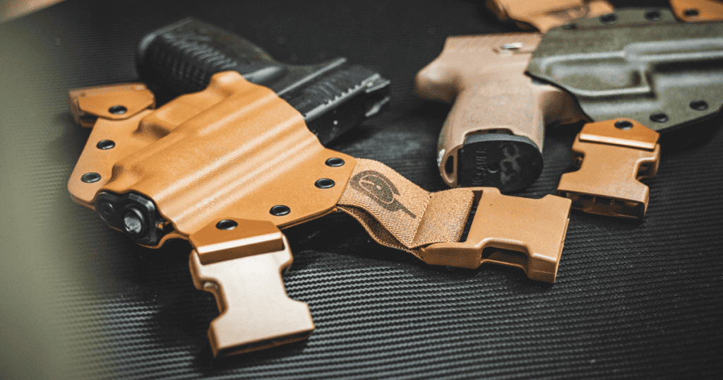 Two GunfightersINC holsters on a dark green table.