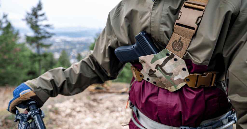 A person mountain biking wearing the GunfightersINC Kenai Chest holster, happy he found the right holster.