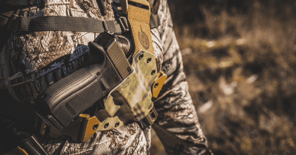 A hunter bear hunting wearing the Kenai Chest Holster by GunfightersINC.