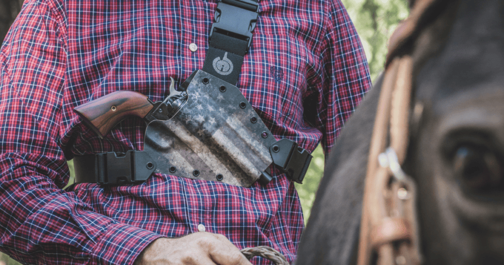 A man wearing a chest holster while riding a horse.