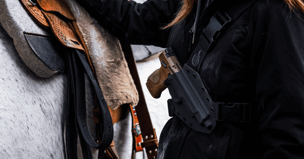 A woman standing next to a horse wearing a chest holster.