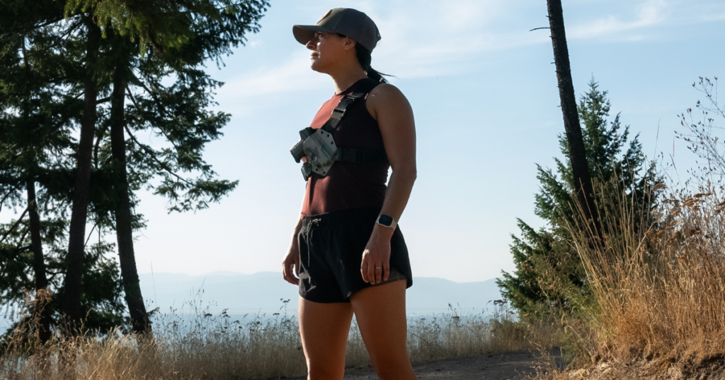 A woman at the end of ther run wearing a chest holster by GunfightersINC.