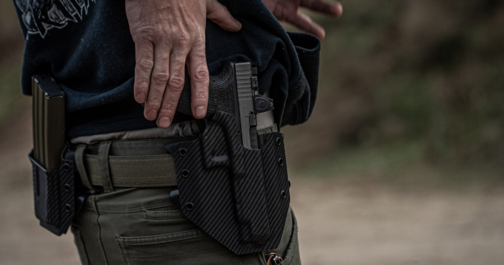 A man wearing an OWB conealed carry holster on his hip.