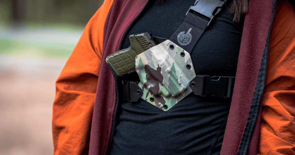 A woman hiking using a Kenai GunfightersInc Chest Holster.