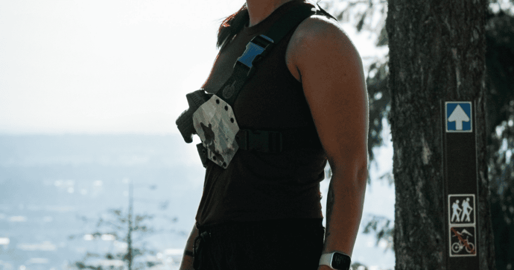 A woman wearing a GunfightersINC Kenai Chest Holster while trail running.