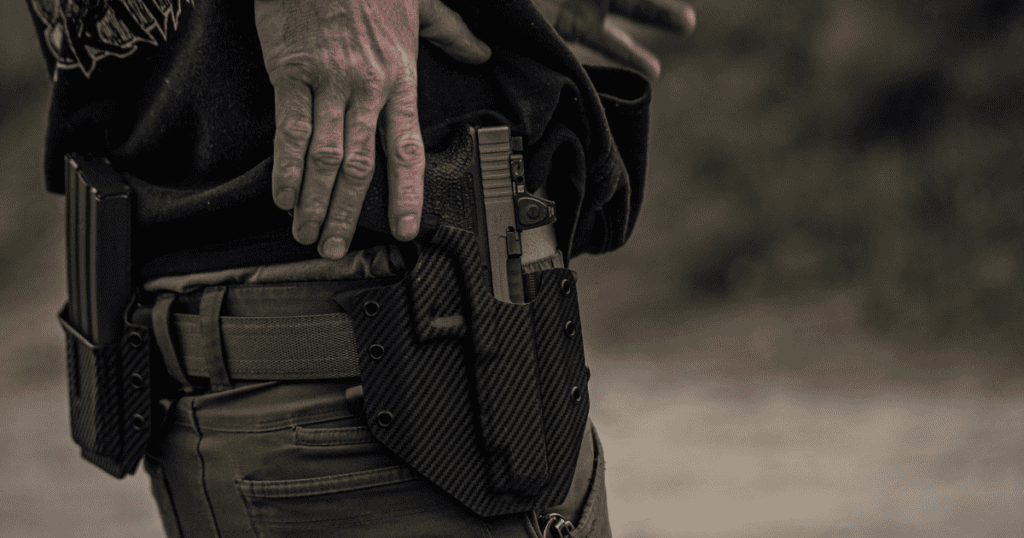 A man about to draw his gun from his GunfightersINC black holster attached to this tactical belt.