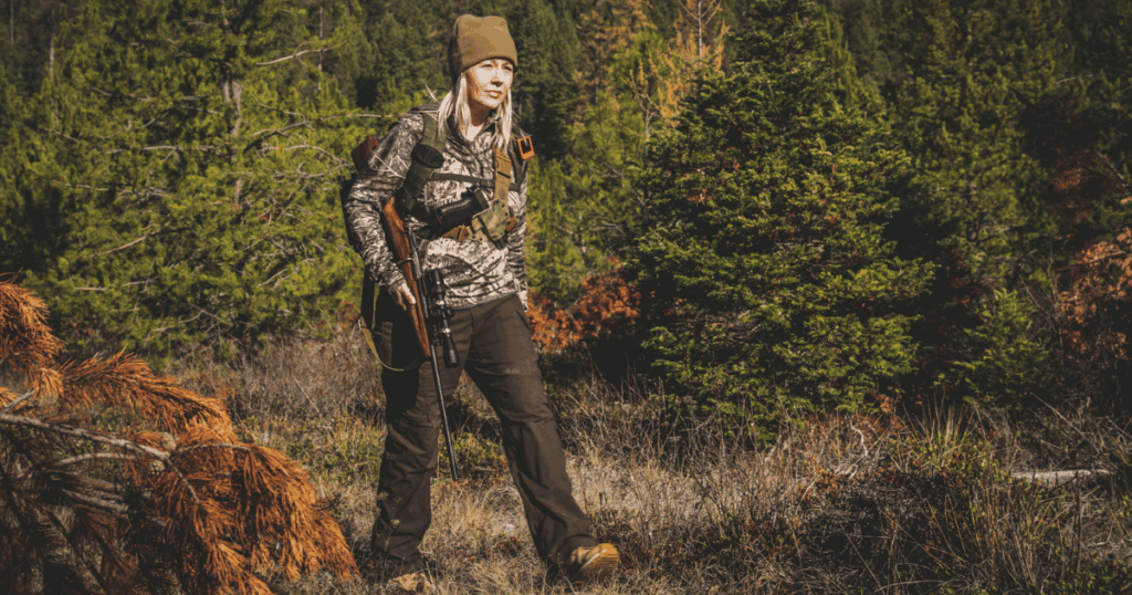 A woman hunter carrying her hunting rifle and backup hunting gun.