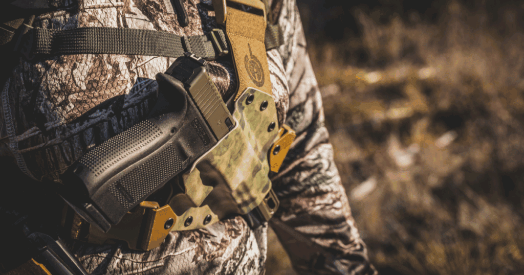 A woman in a hunting jacket wearing the GunfightersINC Kenai Chest Holster to hold her backup hunting gun.