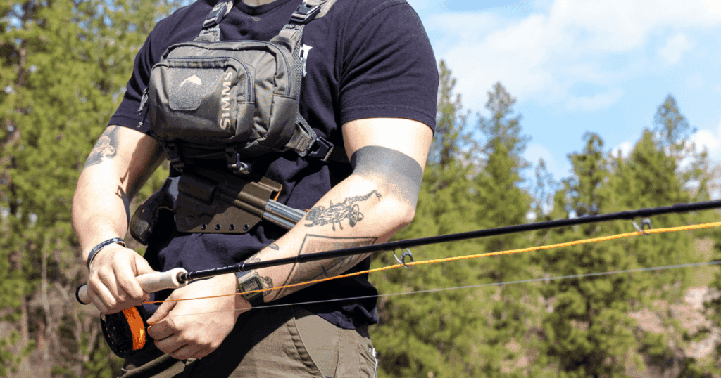 A man out fishing wearing a chest pack with a Tackle Link Holster from GunfightersINC attached.