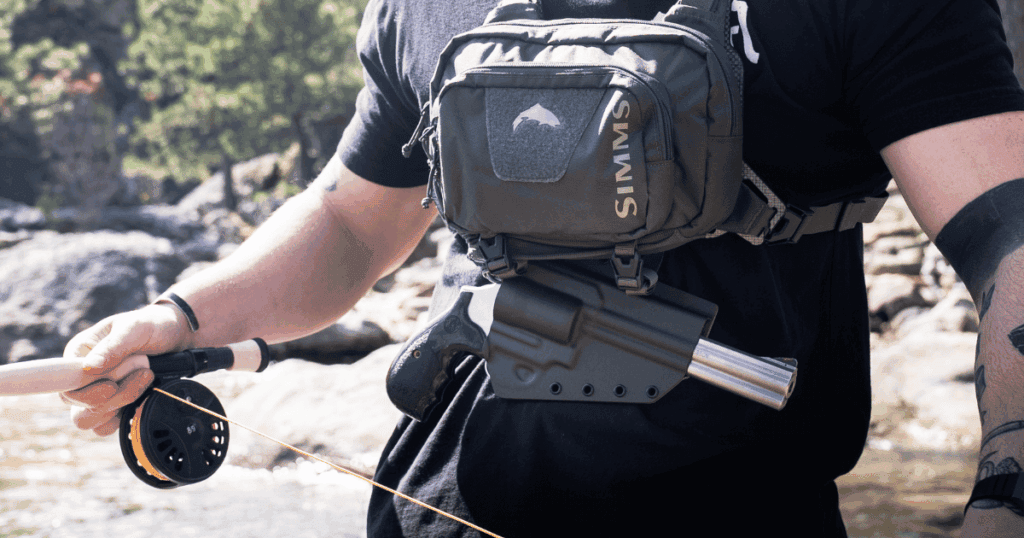A man casting his rod while wearing a tackle chest pack and holster.