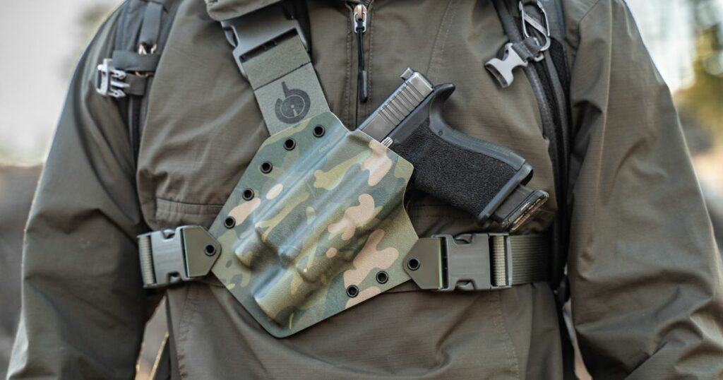 A man wearing the GunfightersINC Kenai Chest Holster while out using his adventure vehicle.