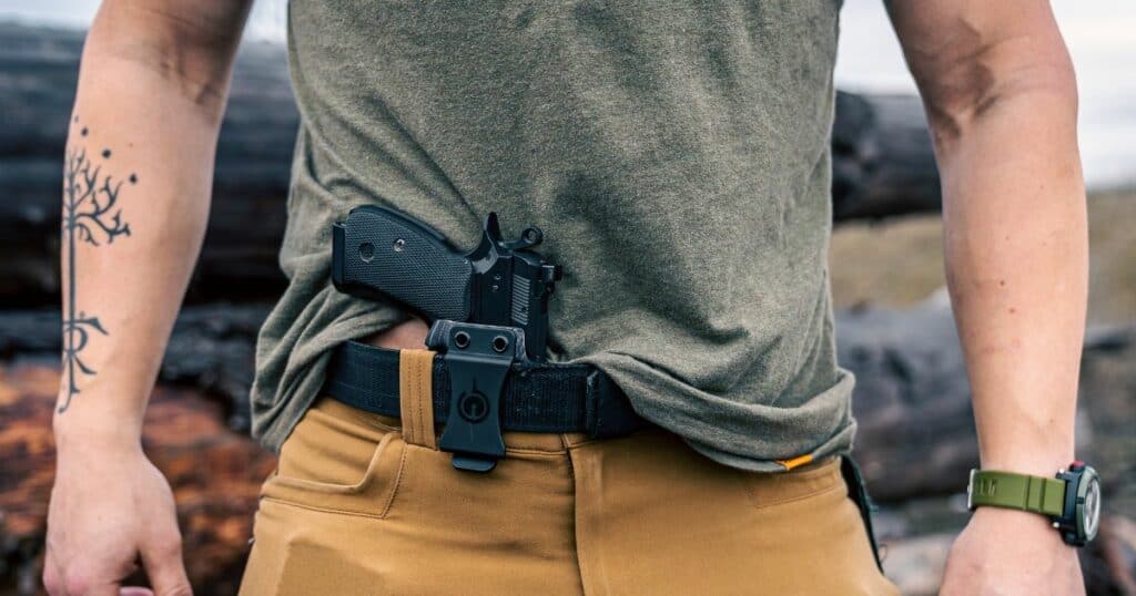 A man carrying his EDC gun along the front of his pants.