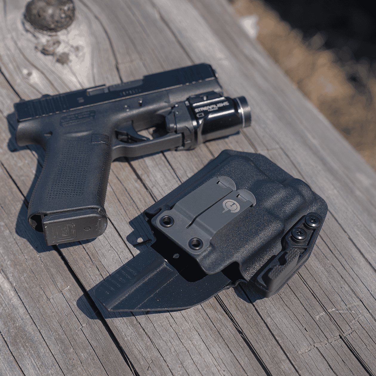 Ready to Ship Light Bearing Wraith Next to Unholstered Pistol on Log