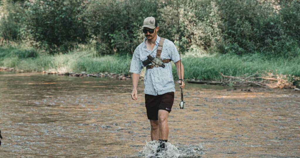 A man wearing a GunfightersINC Kenai Chest Holster while fishing.