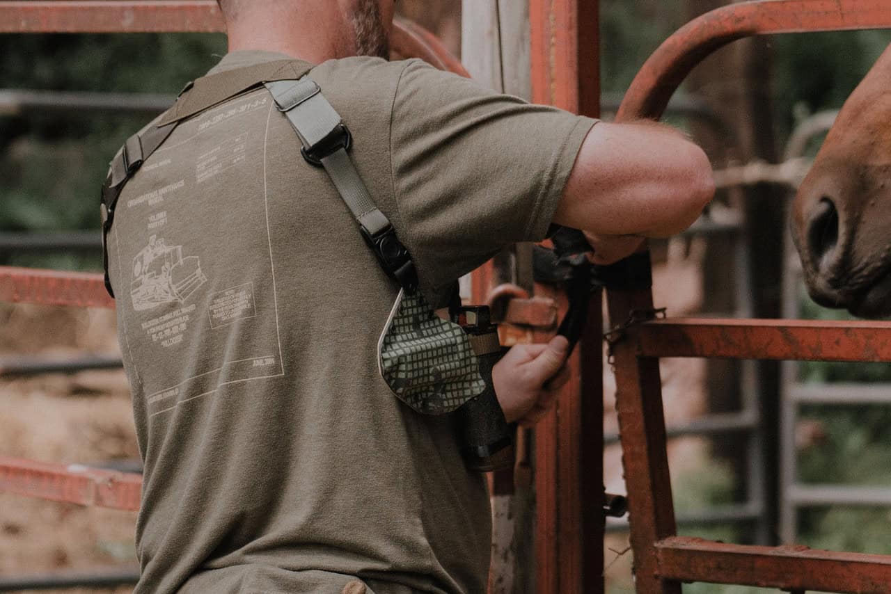 man wearing a spectre lite with leather knuckle in front of gate with horse
