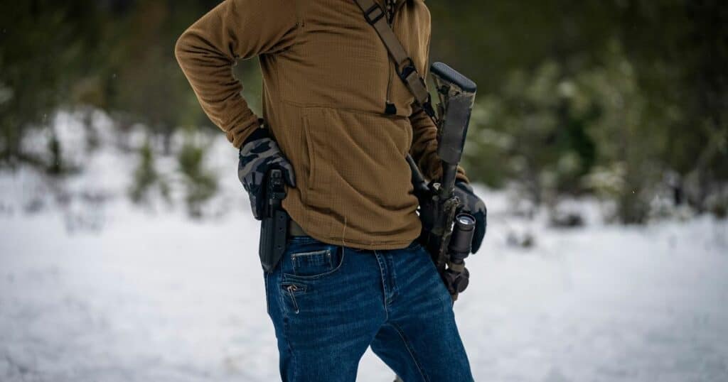 A man getting ready to pull his gun from his GunfightersINC holster while shooting at a range.