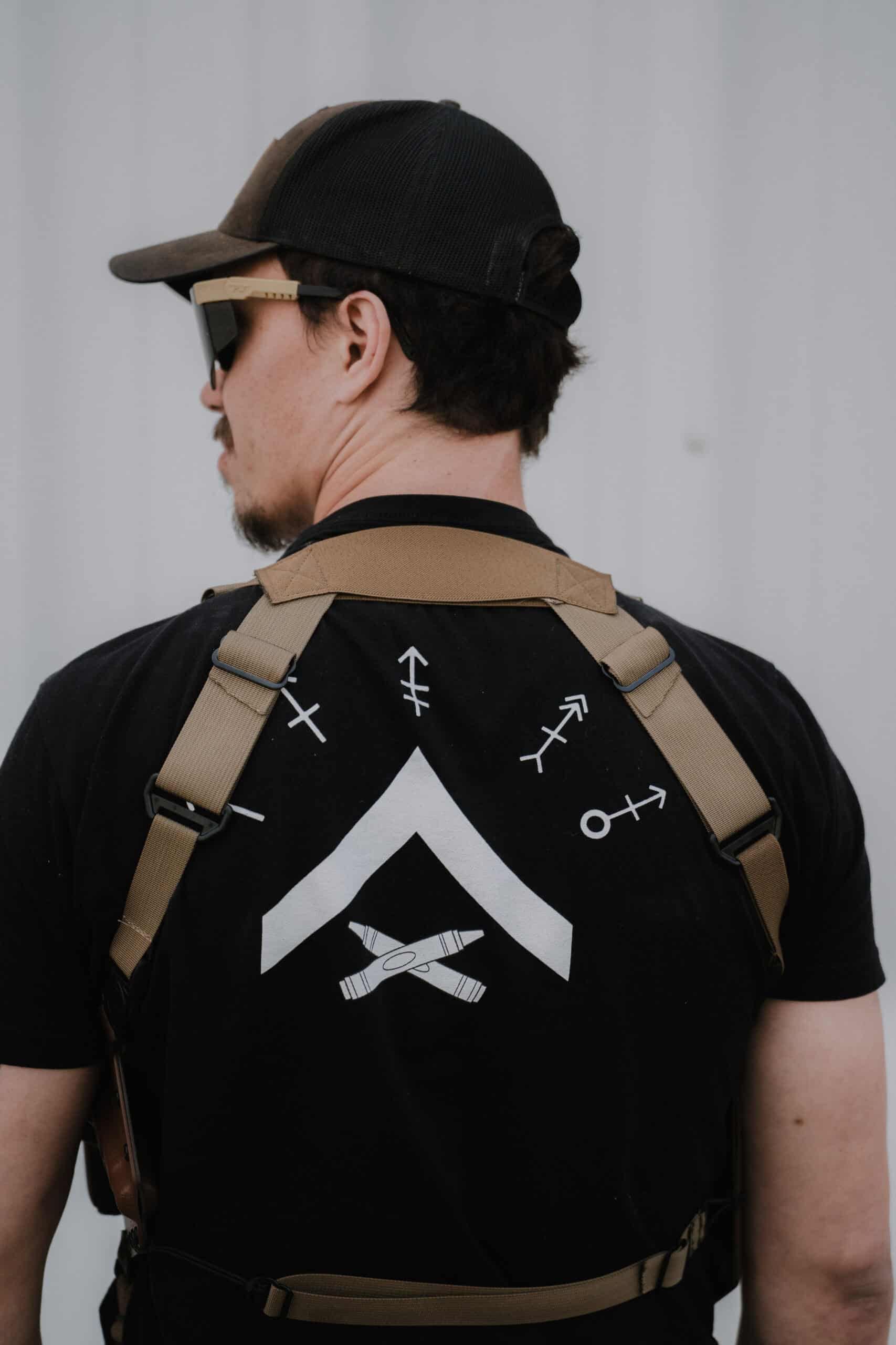 The back of a man wearing a Spectre Shoulder Holster which frames his GunfightersINC t-shirt.