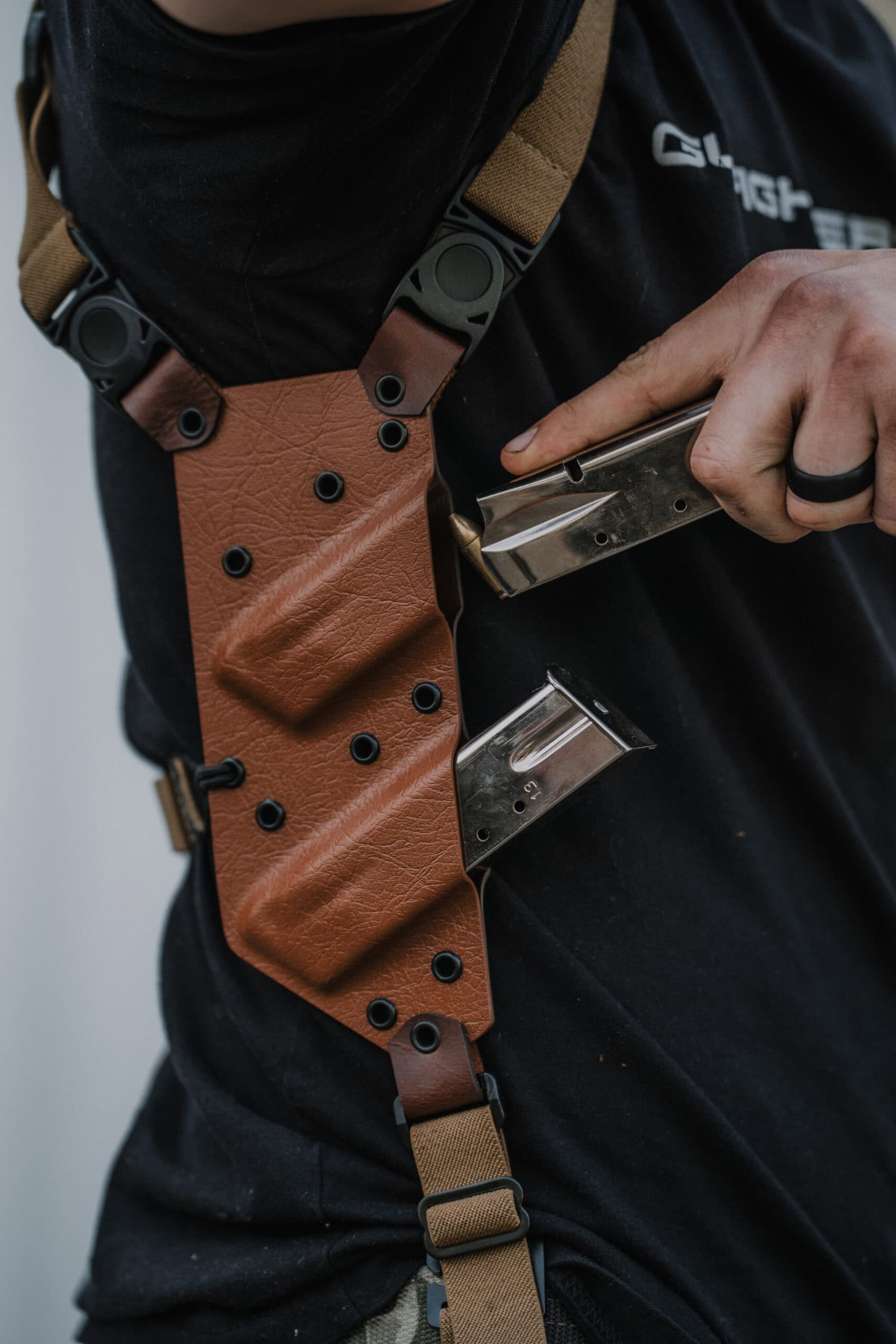 A man removing one of his two magazines from the support side of his Spectre Shoulder Holster.