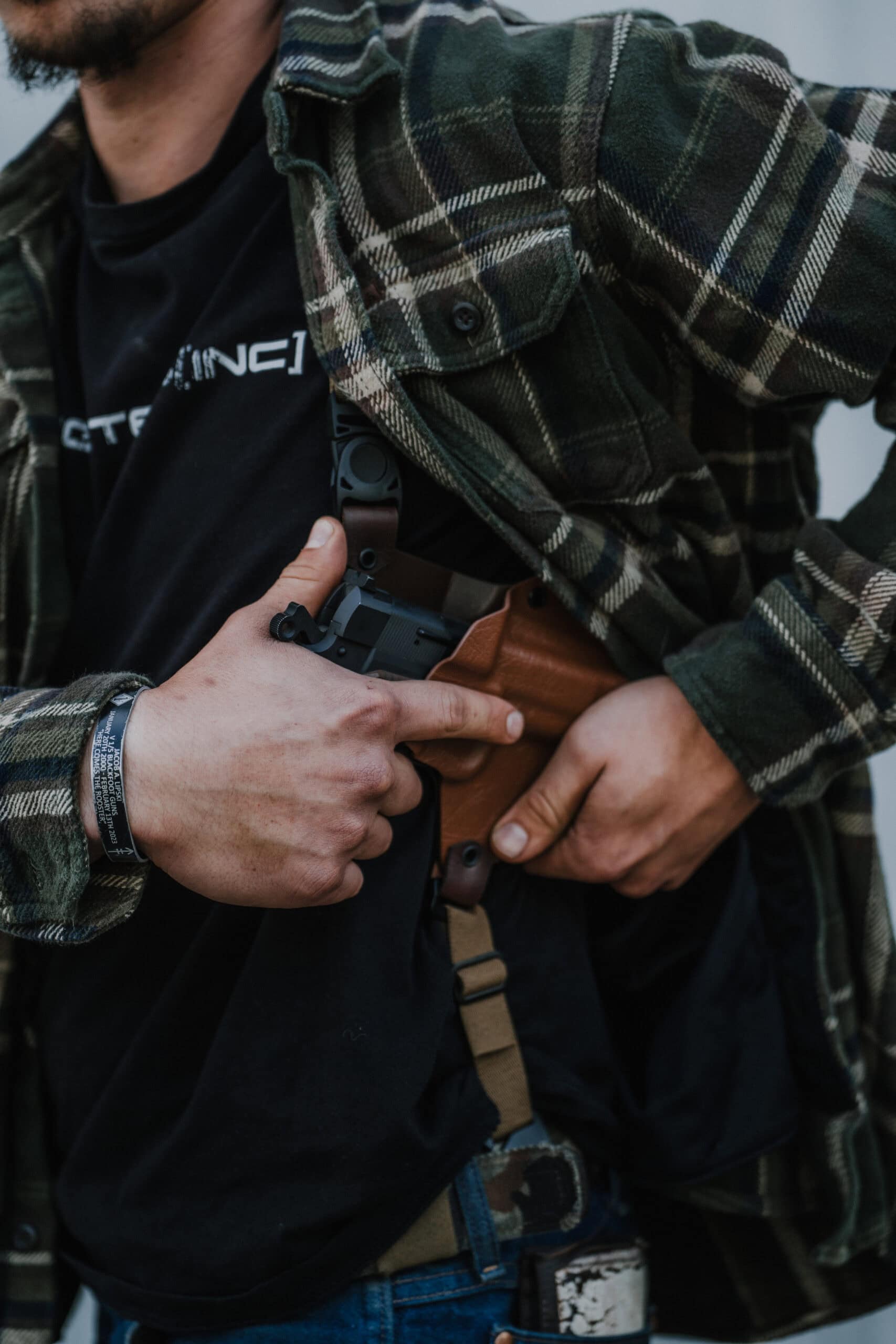 A man pushing aside his flannel and pulling his pistol out of his Spectre Deluxe Holster.