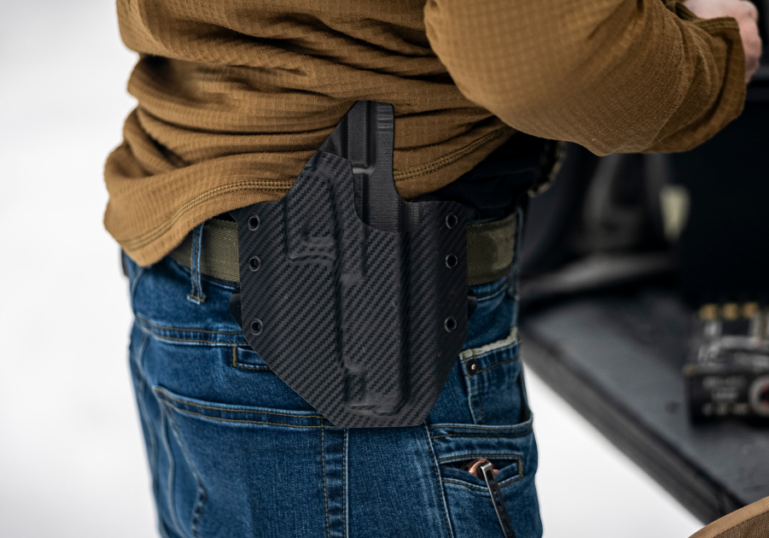 A person wearing an OWB GunfightersINC holster for home defense.