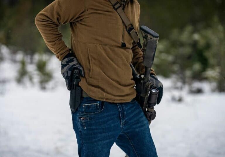 A man getting ready to pull his gun from his GunfightersINC holster while shooting at a range.